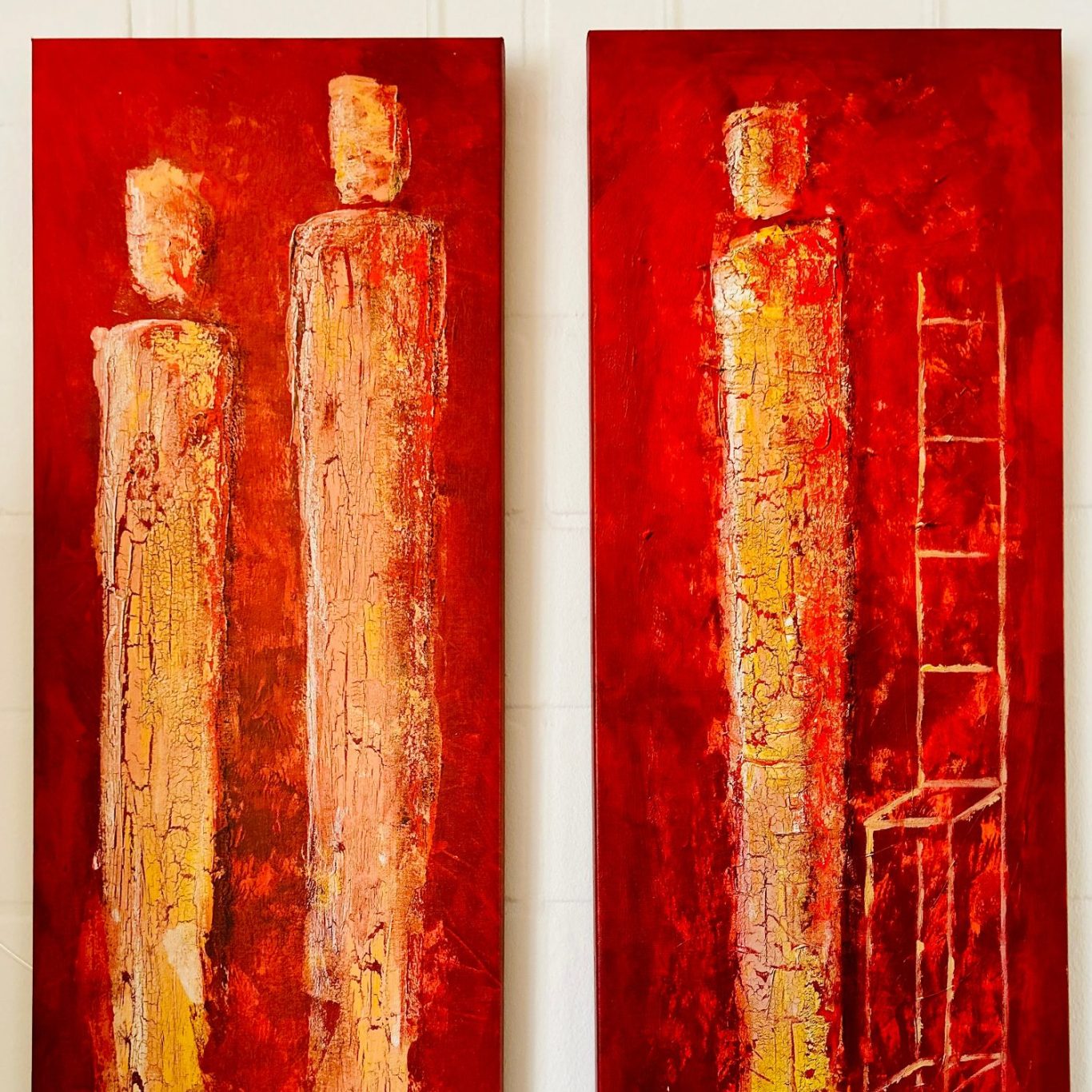 Zwei hohe Figuren mit rot-orangefarbenem Hintergrund und einer Leiter auf der rechten Seite.