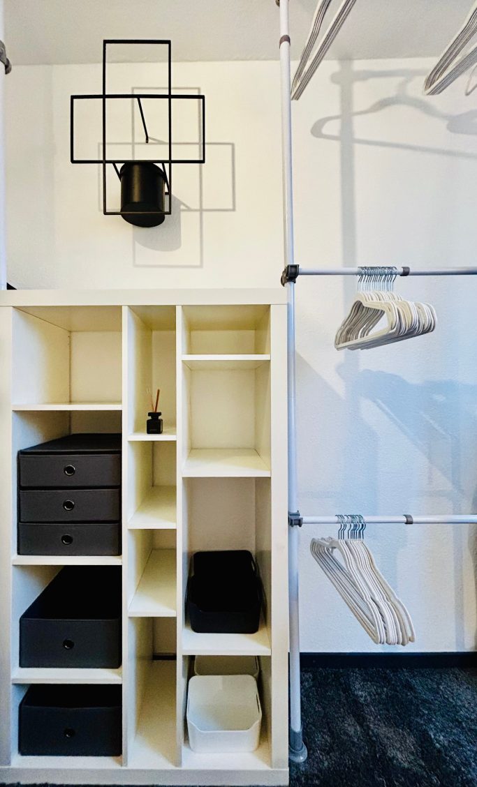 Schmaler, moderner Kleiderschrank mit Regalen, Schubladen und Kleiderstangen.