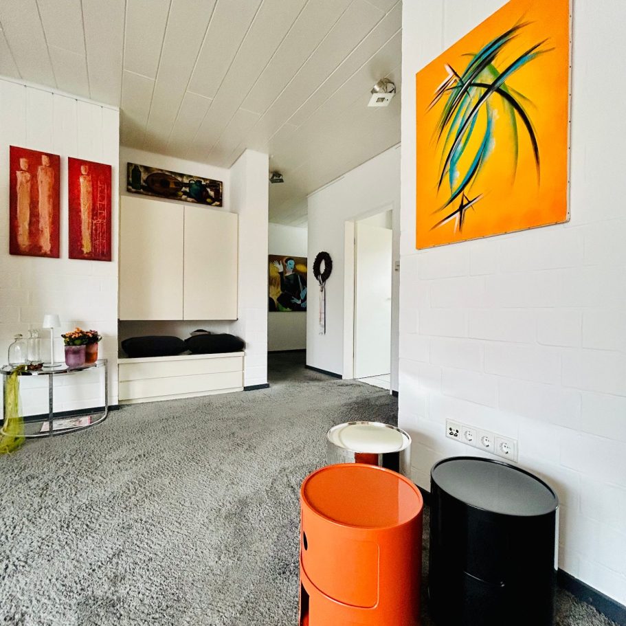 Heller Raum mit Teppich, bunten Aufbewahrungselementen und modernen Wandbildern.