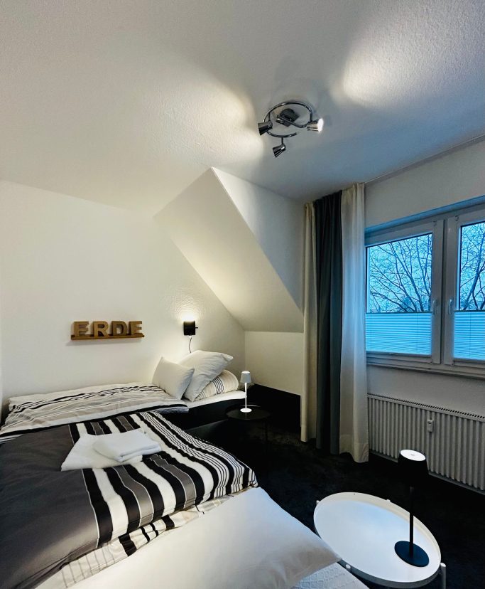 Modernes Schlafzimmer mit zwei Betten, minimalistischem Design und Fenstern mit Aussicht.