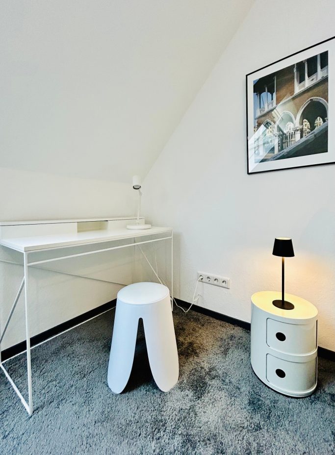 Moderne Ecke mit Schreibtisch, Hocker und einer Lampe neben einem Bild an der Wand.